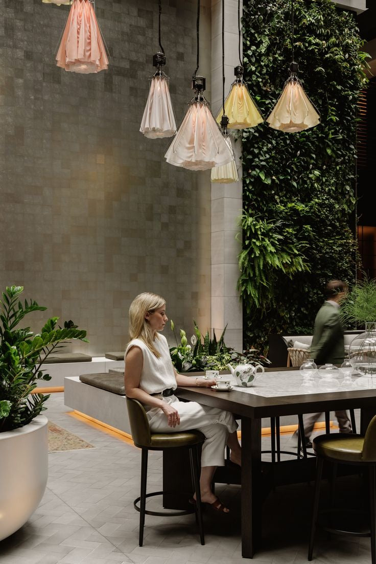 Diners at a courtyard table beneath glass pendant lights and greenery